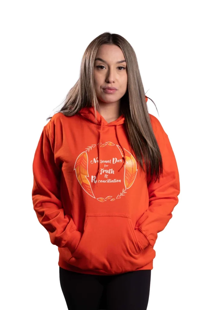 A woman wears an orange hoodie with a logo